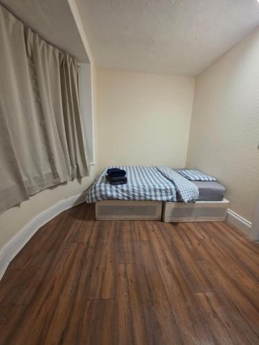 a small bedroom with a bed and a wooden floor at ELI STAY Ensuite rooms in Ipswich