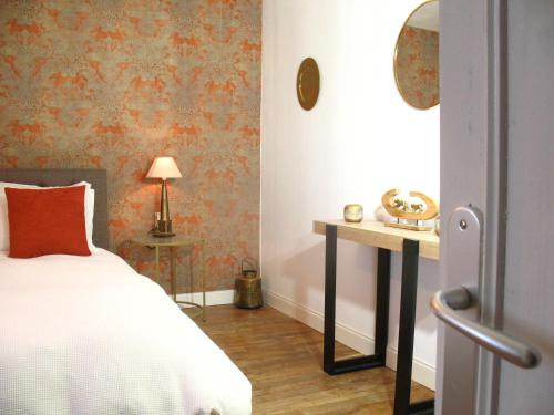 a bedroom with a bed and a table with a lamp at Le Cosy Nid in Leyme