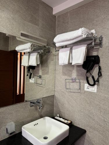 a bathroom with a sink and a mirror and towels at Tashi Tagay Hotel & Apartment in Kathmandu
