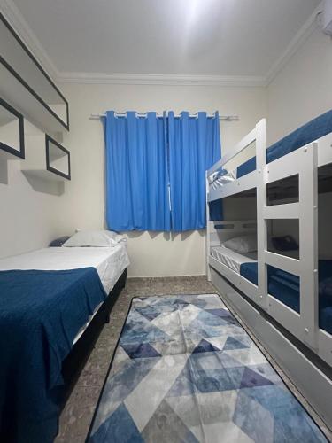 a bedroom with two beds and a blue curtain at Paraiso Particular Piscina e Ar Condicionado in Americana