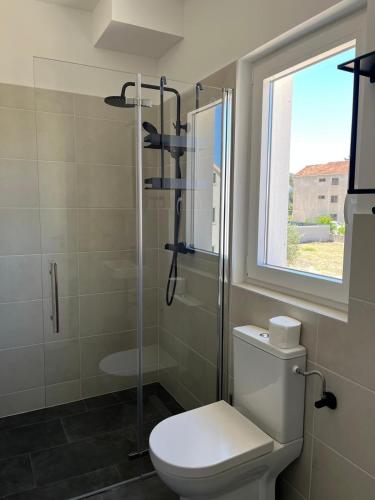a bathroom with a toilet and a shower and a window at BCM Weidinger in Mirce