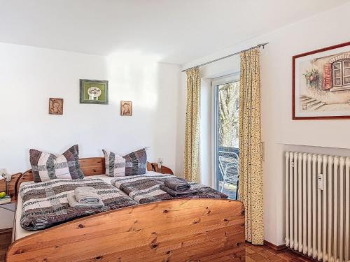 a bedroom with a wooden bed and a window at Apartment Alpenseeblick by Interhome in Seebruck