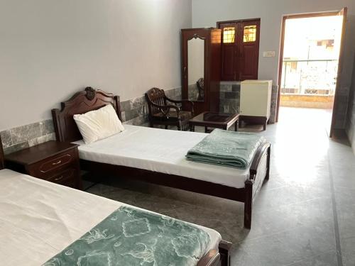 a bedroom with two beds and a table and chairs at Qaiser Hotel in Lahore