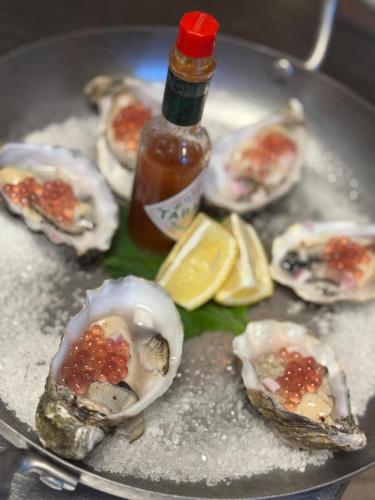 un piatto di ostriche con una bottiglia di salsa e limone di Hotel Amerika a Hoek van Holland