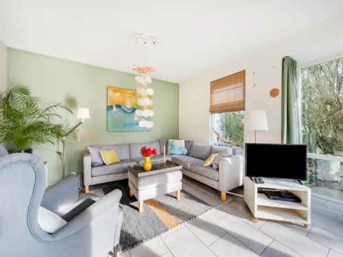 a living room with a couch and a tv at Holiday Home Noordwijk near Beach & Sauna in Noordwijk
