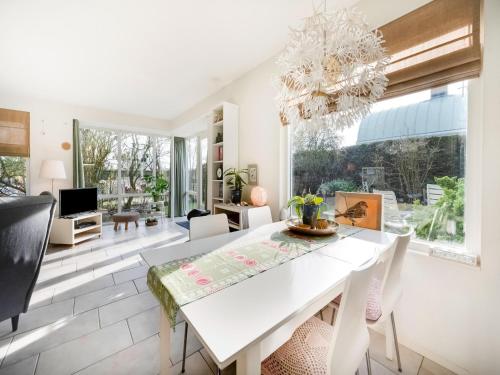 a dining room with a white table and a chandelier at Holiday Home Noordwijk near Beach & Sauna in Noordwijk