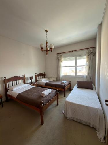 a bedroom with three beds and a window at Departamento Torraca VII in Comodoro Rivadavia