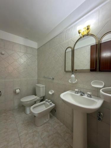a bathroom with a sink and a toilet and a mirror at Departamento Torraca VII in Comodoro Rivadavia
