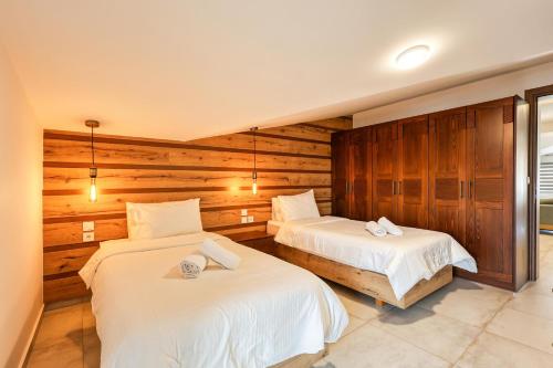 two beds in a room with wooden walls at Meteora View Penthouse in Kalabaka