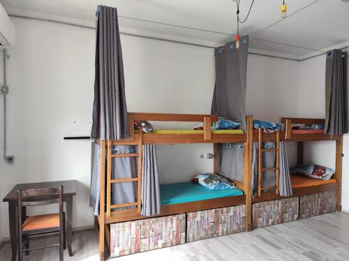 a room with two bunk beds with a table and a desk at Roof Top Hostel in Tirana