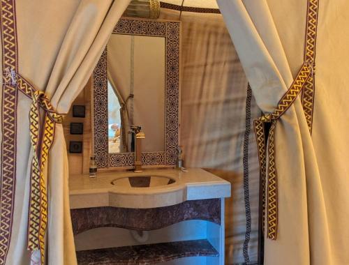 a bathroom with a sink and a mirror at Milagro Luxury Camps in Merzouga