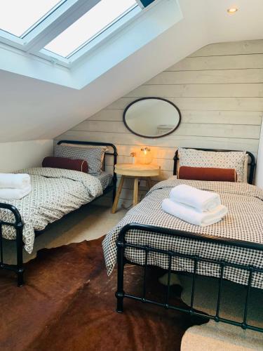 a attic room with two beds and a table at Peartree Cottage in Sandhoe