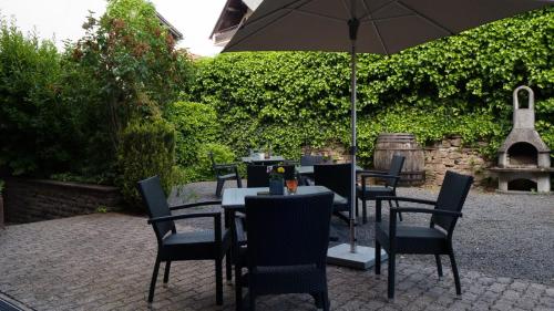 a patio with tables and chairs with an umbrella at Hotel Kachelburg in Dieblich