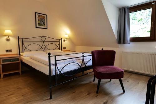 a bedroom with a bed and a chair and a window at Hotel Kachelburg in Dieblich