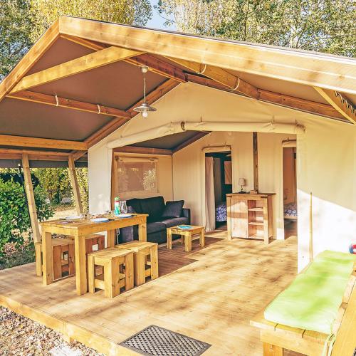 a patio with awning and a couch and tables at Camping La Pointe du Talud in Ploemeur