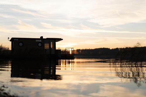 a house in the middle of a body of water at Houseboat Pałuki in Sobiejuchy