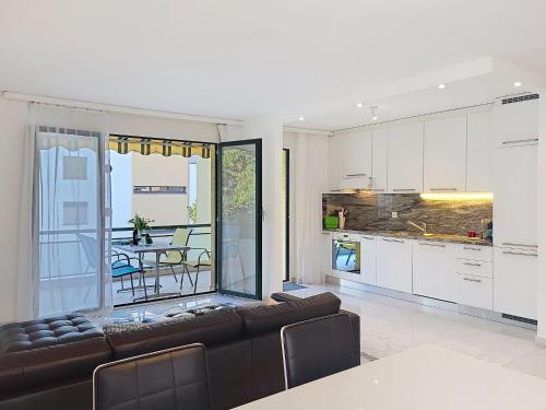 a living room with a leather couch and a kitchen at Apartment Apt- Hermosa by Interhome in Locarno