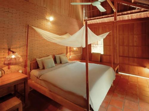 a bedroom with a bed with a mosquito net at Le Mékong Vert Ecolodge in Ben Tre