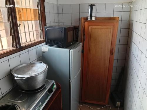 una piccola cucina con un forno a microonde sopra un frigorifero di Shine town house a Yaoundé