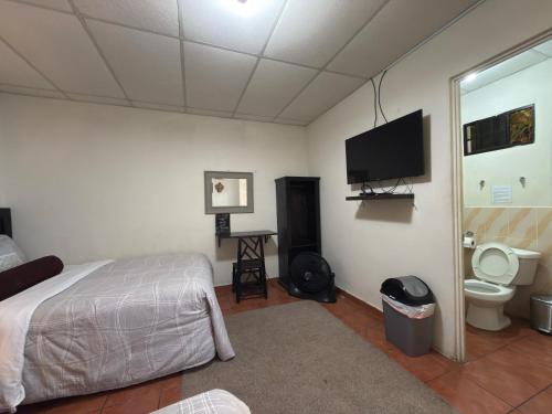a bedroom with a bed and a toilet and a tv at Los Portones de Ataco in Concepción de Ataco