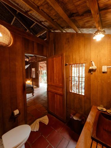 a bathroom with a toilet in a room with wooden walls at Le Mékong Vert Ecolodge in Ben Tre