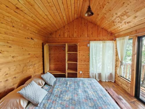 a bedroom with a bed in a wooden room at Cabaña Ardilla Corralillo in Corralillo