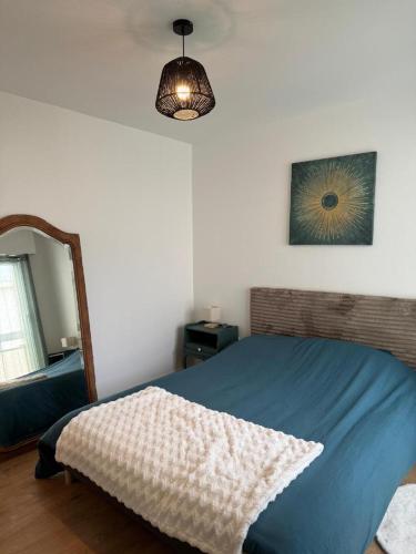 a bedroom with a blue bed and a mirror at Les Trinitaires in Sarzeau