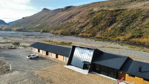 a building with a black roof next to a mountain at Hosteria Manzano Amargo in Manzano Amargo