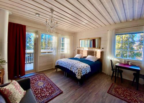 a bedroom with a bed with a wooden ceiling and windows at Villa Happy Fox in Rovaniemi