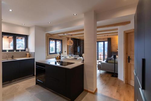 a kitchen with black cabinets and a living room at Alpine Hygge by Villars Luxury in Villars-sur-Ollon