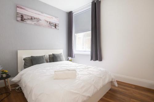 a bedroom with a white bed with a window at Seafront Flat in Brighton Marine Parade in Worthing