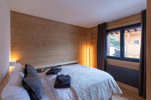 a bedroom with a bed with a wooden wall at Alpine Hygge by Villars Luxury in Villars-sur-Ollon