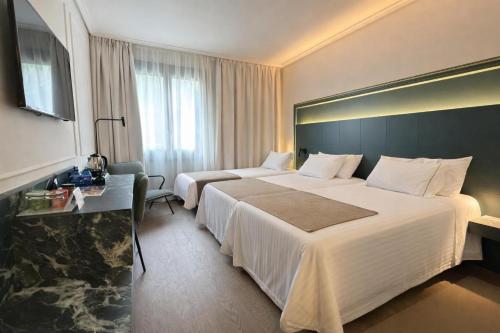 a hotel room with two beds and a desk at Silken Gran hotel Durango in Durango