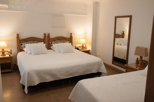 a hotel room with two beds and a mirror at Hotel Santamaria INN in La Ceja