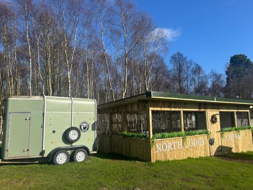 a green trailer parked in front of a small building at North Lodge Glamping in Carnwath