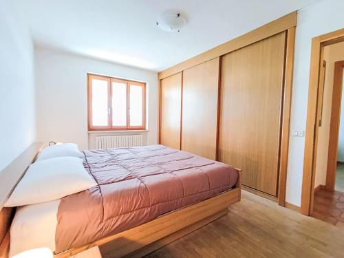 a bedroom with a large bed and wooden cabinets at Apartment Casa Dalpi by Interhome in Predazzo