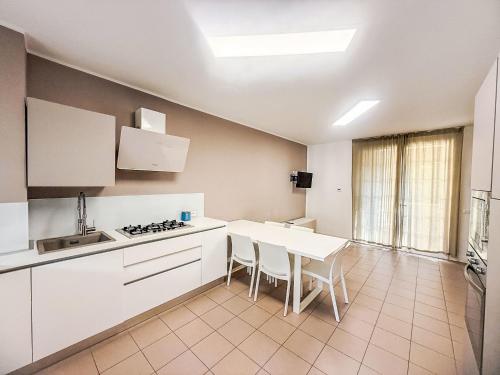 a kitchen with white cabinets and a table with chairs at Holiday Home Veranda-2 by Interhome in Rosapineta