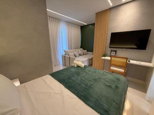 a bedroom with a bed and a couch and a television at Apartamento com suíte e sala com ar-condicionado in Barreiras