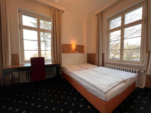 a small bedroom with a bed and two windows at Hotel Galleria in Munich