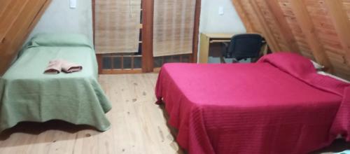 a bedroom with a bed with a pink blanket and pair of shoes at Cabaña don Cencio in San Pedro