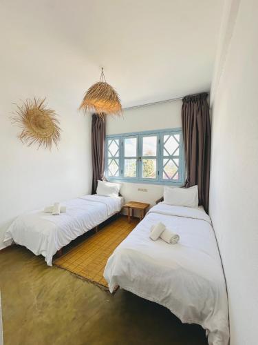 a room with two beds and a window at Appartement Michel Uniquement les familles in Oualidia