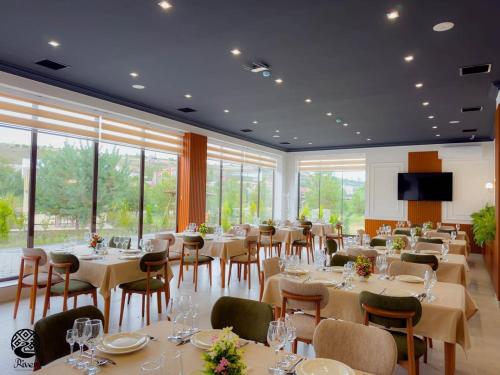 a dining room with tables and chairs and windows at River Hotel Restaurant in Quba