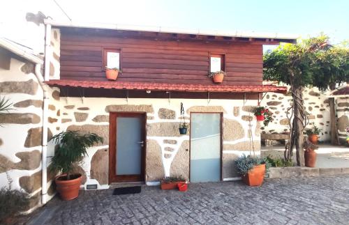 a stone house with two doors and potted plants at CoutoRural in Vila Nova de Gaia