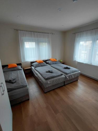 a bedroom with two beds and two windows at Borti Apartman in Zamárdi