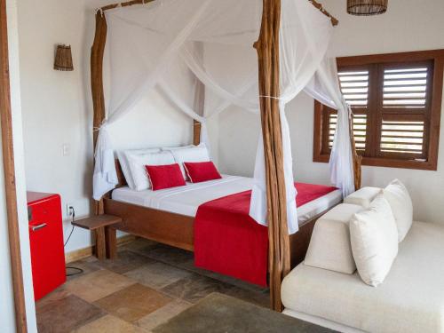 a bedroom with a canopy bed and a couch at Pousada Fortal Preá in Prea