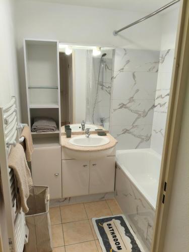 a bathroom with a sink and a shower and a tub at Cocon douillet près de l'étang in Mèze