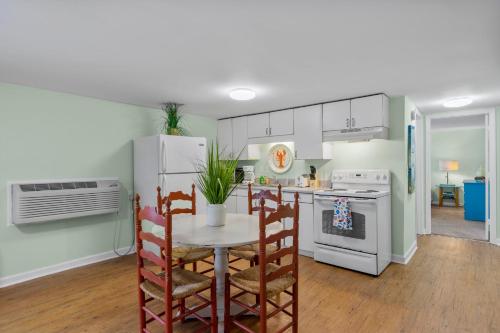 a kitchen with a table and a white refrigerator at Sand Dollar Suites 1 in Carolina Beach