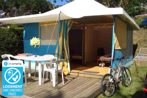 a tent with a table and a bike parked in front of it at ZEcamping 4 étoiles chiens acceptés tennis piscine chauffée in Salles-Curan
