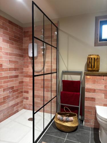 a bathroom with a glass shower with a toilet and a basket at The Cabin in St. Ives