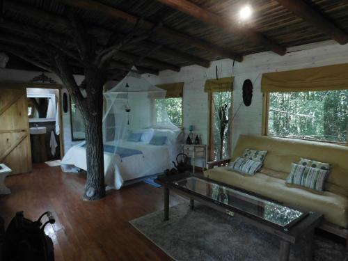 a bedroom with a bed and a couch and a tree at La Casa Del Arbol con pileta privada in Capilla del Señor